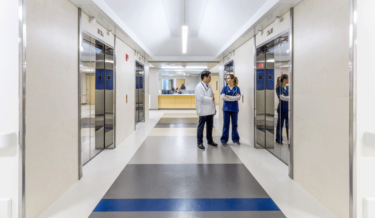 Blend porcelain tile panels on elevator bank walls and corridor in hospital